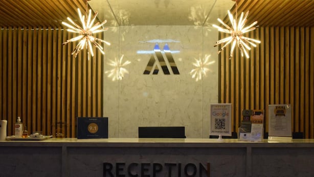 A reception desk with a marble top, a sign reading "RECEPTION," and two starburst light fixtures.