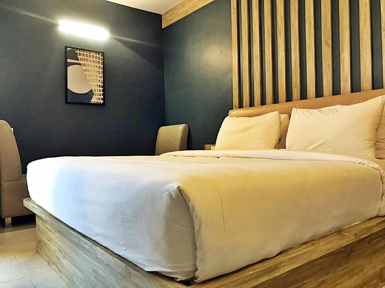 A bed with a wooden headboard, a bedside table, and a wall-mounted light fixture.