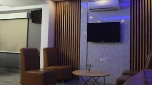 A modern lounge area with leather sofas, a round table, and a mounted TV.