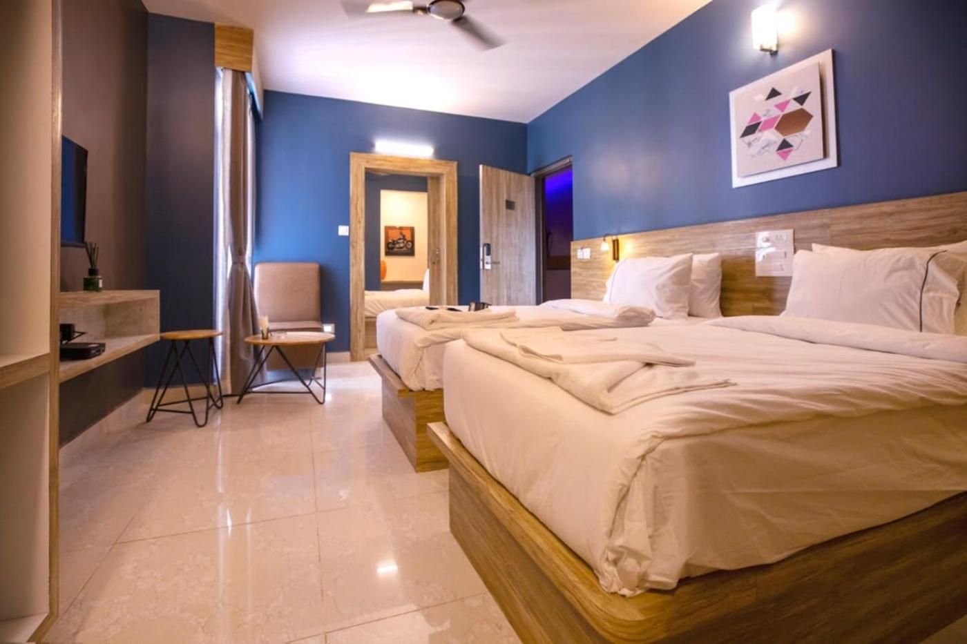 Ein Hotelzimmer mit einem großen Bett, einem Sessel, einem kleinen Tisch und einem Spiegel.