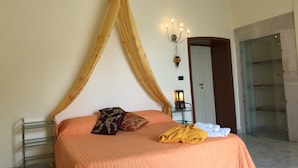 A bedroom with a bed, a canopy, a nightstand with a lamp, and a door. - Chantale's posada (Giovinazzo)