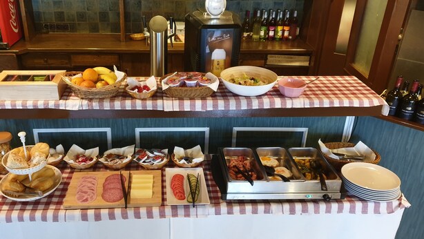 A buffet setup with various food items and condiments. - Hotel Gaya (Bad Soden am Taunus)