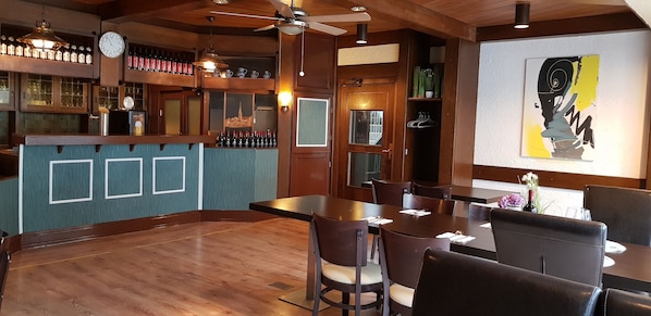 A restaurant with wooden interiors, a bar area, and a large abstract painting on the wall. - Hotel Gaya (Bad Soden am Taunus)