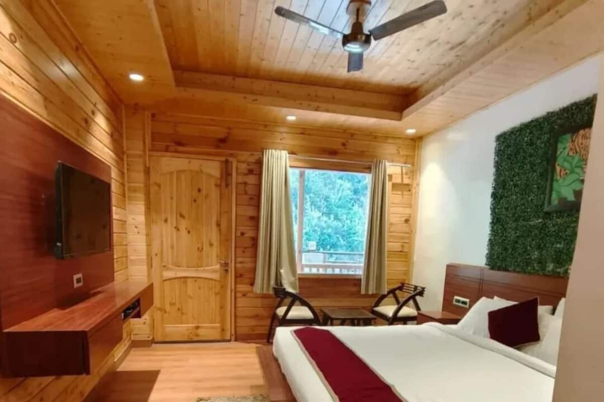 Ein schlicht eingerichtetes Schlafzimmer im Blockhausstil mit Bett, Fernseher, Balkon und einer grünen Wand.