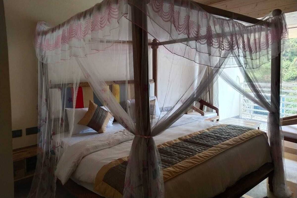Ein Himmelsbett mit Baldachin, ein Holz-Kopfende und Blick ins Grüne.