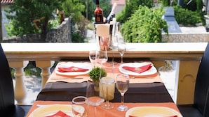 Une table dressée pour deux personnes, avec des verres à vin, une bouteille de vin et un petit vase.