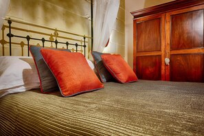 A bed with a metal frame, two pillows, a wooden wardrobe, and a wall with a textured surface.