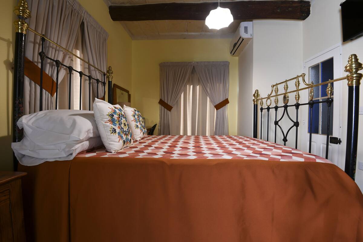 A bedroom with a bed, curtains, and a ceiling light.