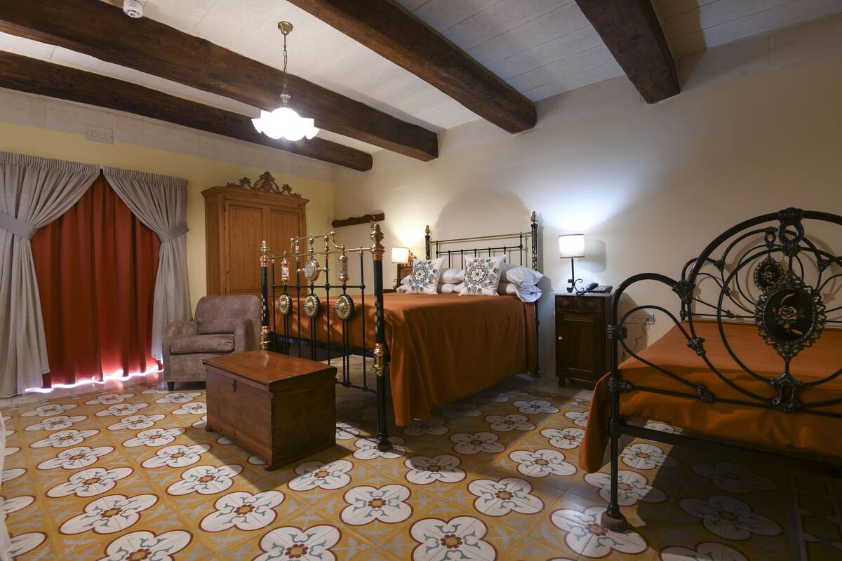 A room with a bed, a chair, a wooden cabinet, and a patterned floor.