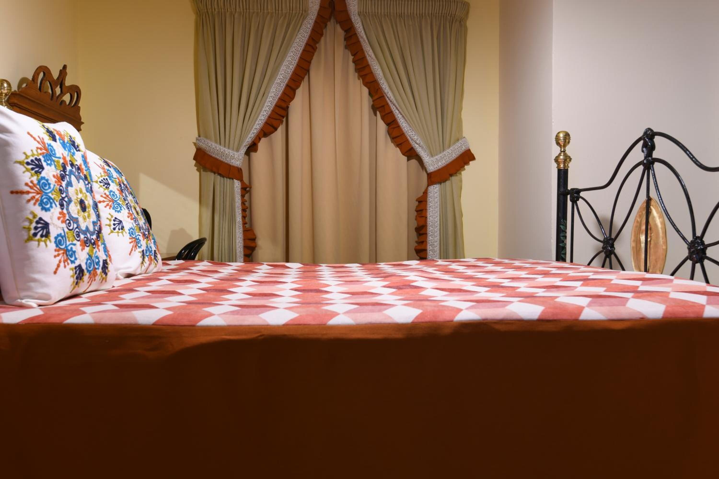 A bed with a checkered bedspread, a decorative pillow, and a canopy with drapes.