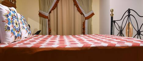A bed with a checkered bedspread, a decorative pillow, and a canopy with drapes.