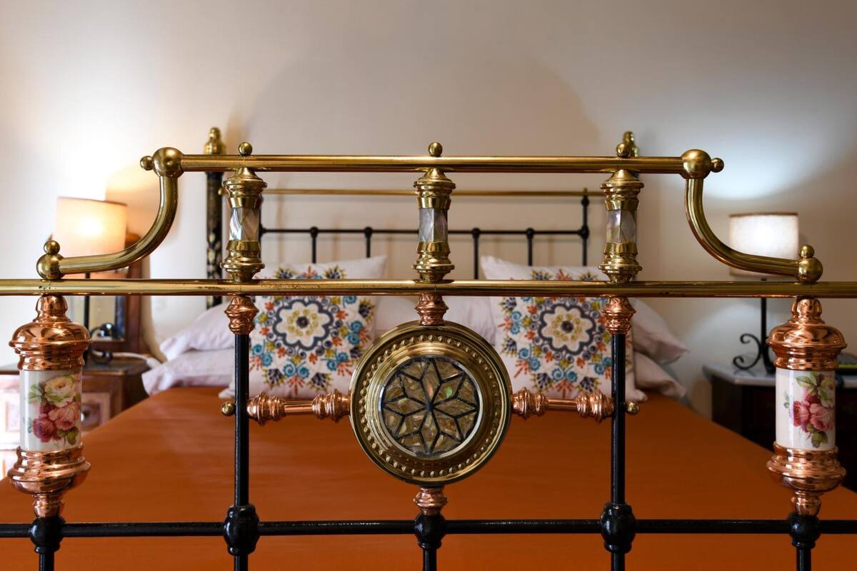 A bed with a metal headboard and a decorative glass center.