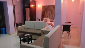Habitación de hotel con sofá, una mesita, cama con cortinas y escritorio con silla.