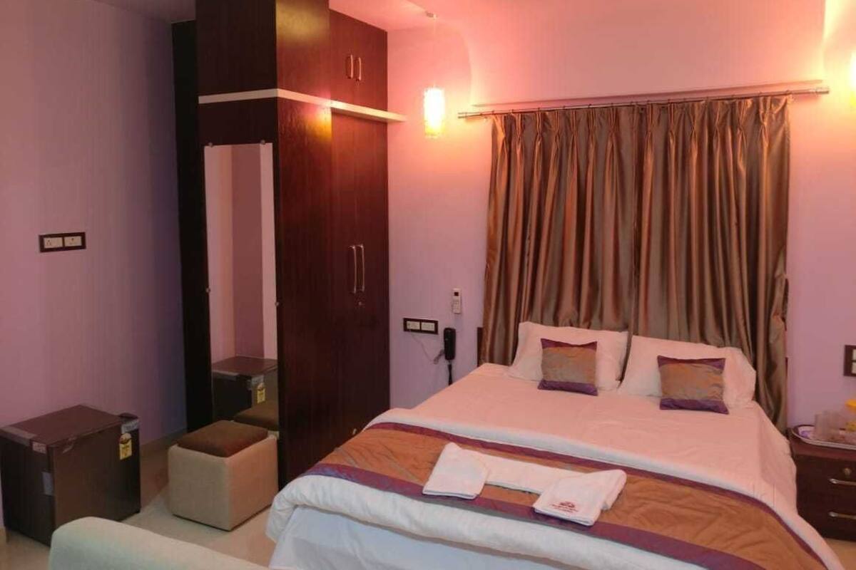 Une chambre d’hôtel avec un lit, une armoire, une table de chevet et une lampe.