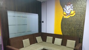 Un sofá modular marrón con cojines beige en una habitación con un separador de vidrio y un mural en la pared.
