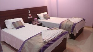 Two single beds with wooden headboards, white bedding, and purple accents. - Sai Guest House (Nagpur)