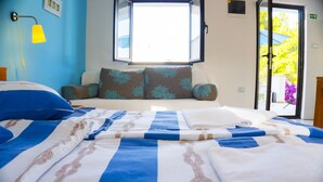 A neatly made bed with blue and white bedding, a window with a view of greenery, and a yellow wall lamp. - Victorious VIScovery Red (Vis)