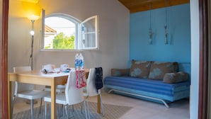 A room with a wooden ceiling, a dining table with chairs, a sofa with patterned cushions, and two hanging plants. - Victorious VIScovery Red (Vis)