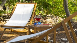 A wooden chair with a white canvas, a small wooden table with a glass of red liquid, and a book. - Victorious VIScovery Red (Vis)