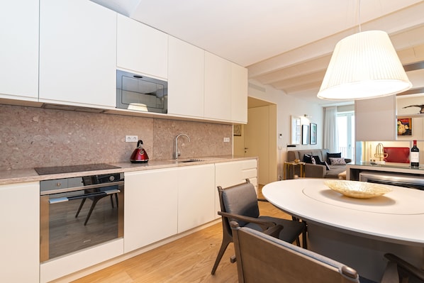 A modern kitchen with white cabinets, a built-in oven, and a large island with a bowl.