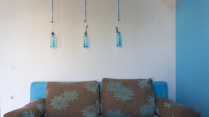 A room with a sofa against a wall, three hanging light fixtures, and a power outlet. - Victorious VIScovery Green (Vis)