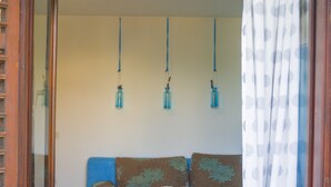 A cozy seating area with a wooden table, a patterned cushion, and three hanging blue vases. - Victorious VIScovery Green (Vis)