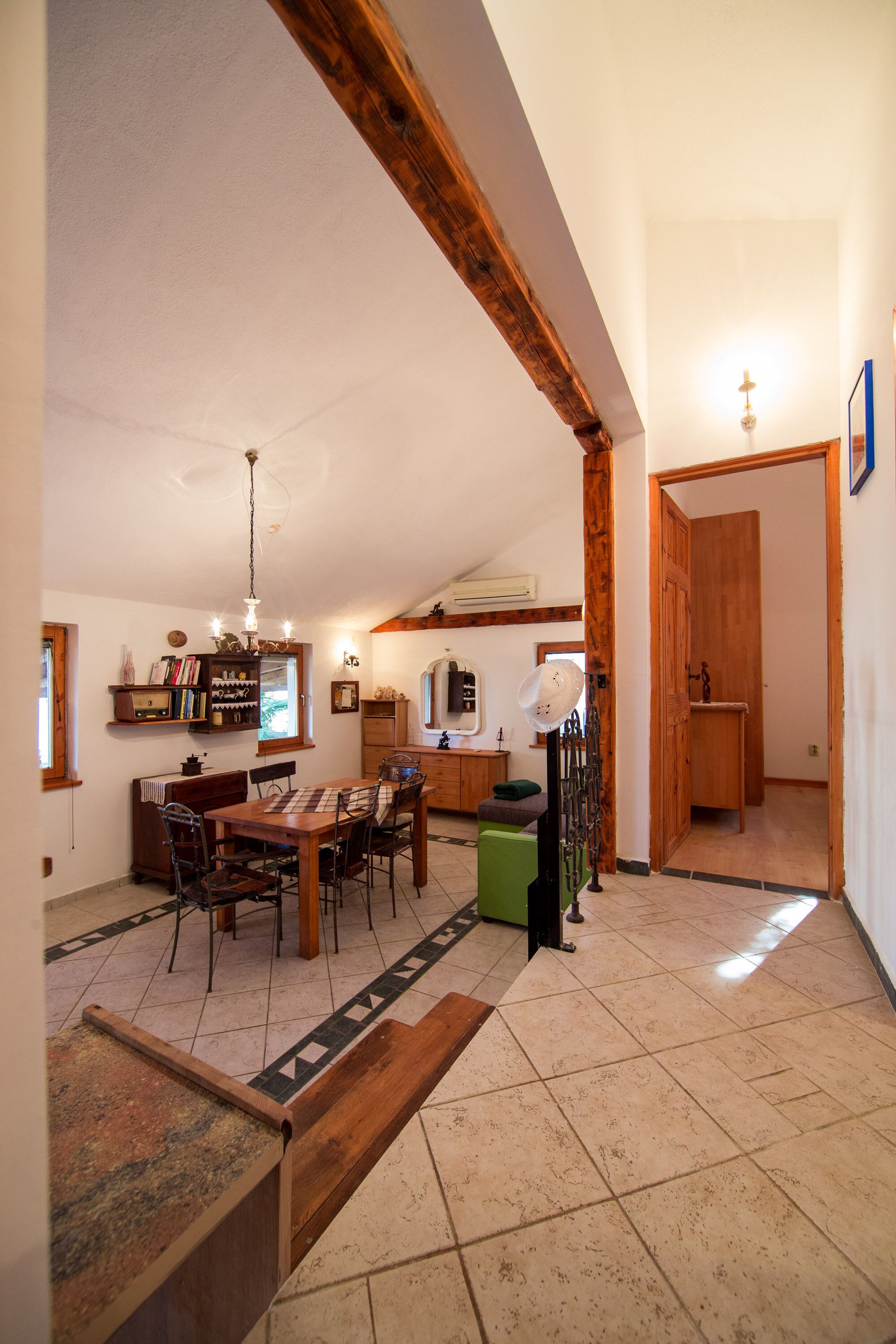 Un comedor con mesa y sillas de madera, una araña y una zona de cocina con pileta y alacenas.
