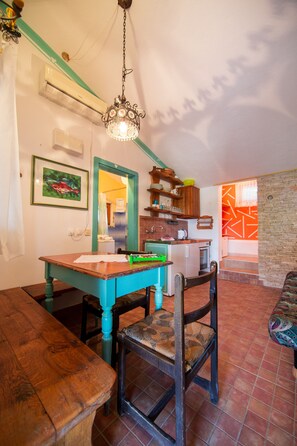 A cozy kitchen with a wooden table, chairs, and a hanging light fixture.