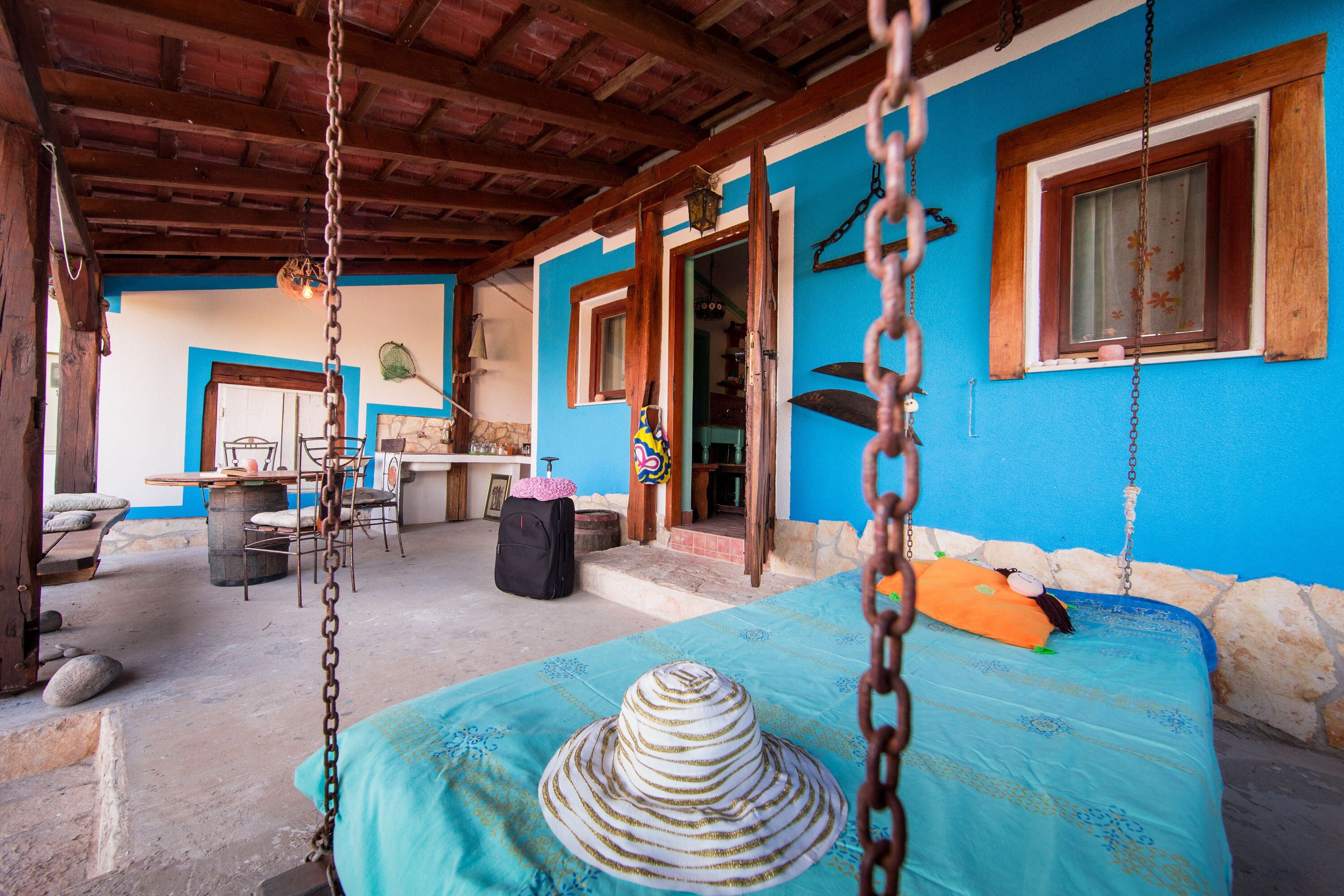 A room with a bed, a hanging chair, and a table with chairs.