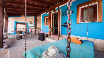A room with a bed, a hanging chair, and a table with chairs.