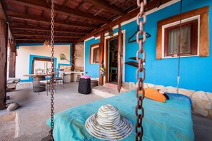 Una habitación con una cama, una silla colgante y una mesa con sillas.