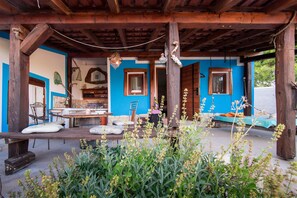Una estructura de madera rústica con exterior azul, un comedor con mesa y sillas, y un colgador con lámpara.