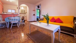 Una sala de estar con una mesa blanca, un sofá amarillo y un comedor con sillas y una mesa.