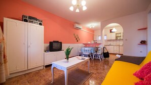 Un espacio habitable compacto con comedor, kitchenette y sofá.