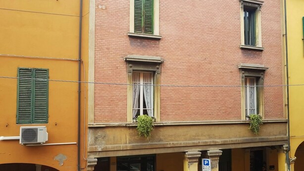 A multi-story building with a brick facade and green shutters. - Casa Bella del Borgo 2 (Bologna)