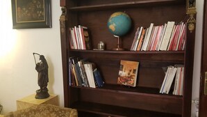 A wooden bookshelf with books, a globe, and a statue. - Casa Bella del Borgo 2 (Bologna)