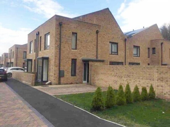 A row of modern brick houses with a paved driveway and small front yards.