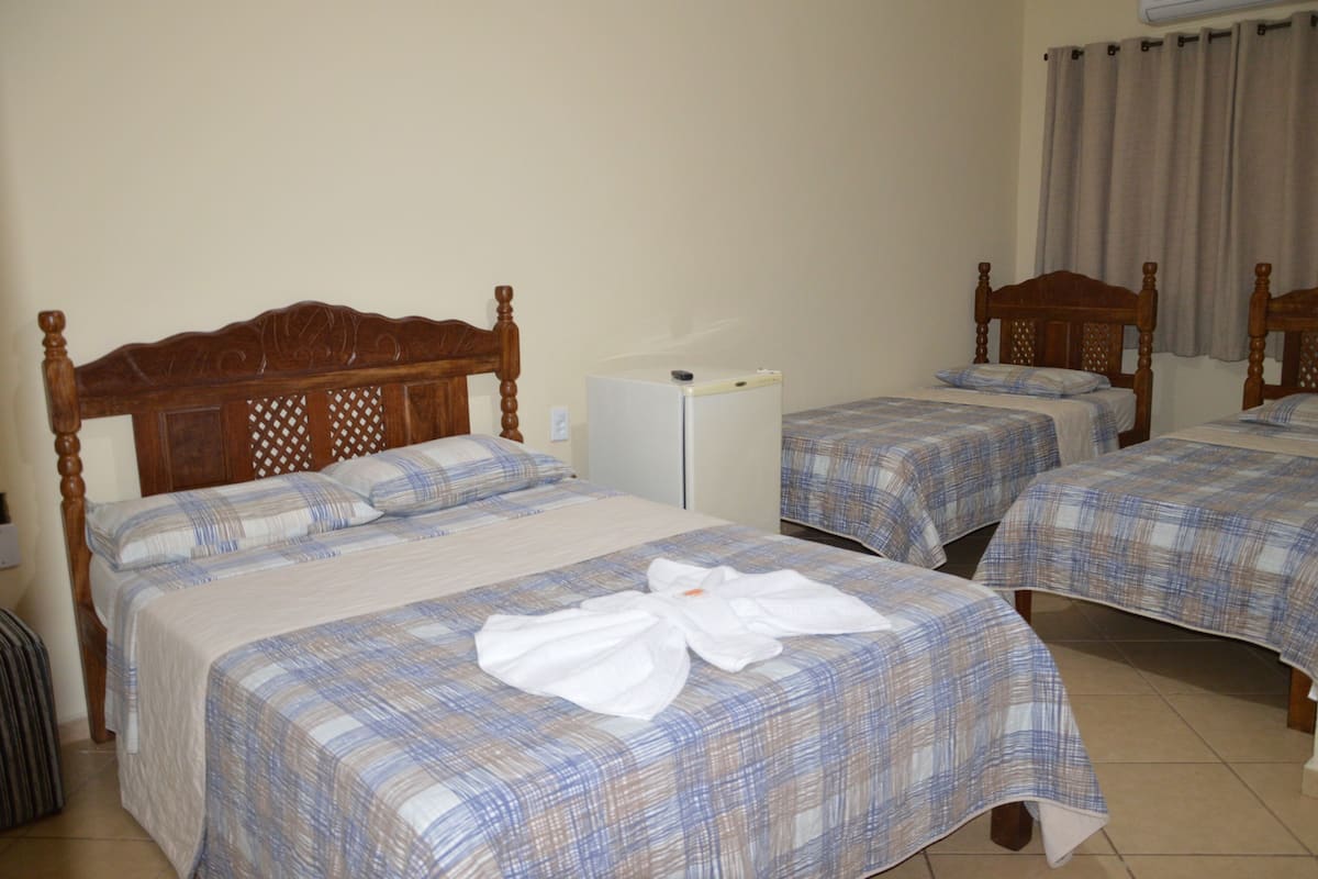 Ett hotellrum med två separata sängar, ett litet vitt kylskåp och en sänggavel i trä.