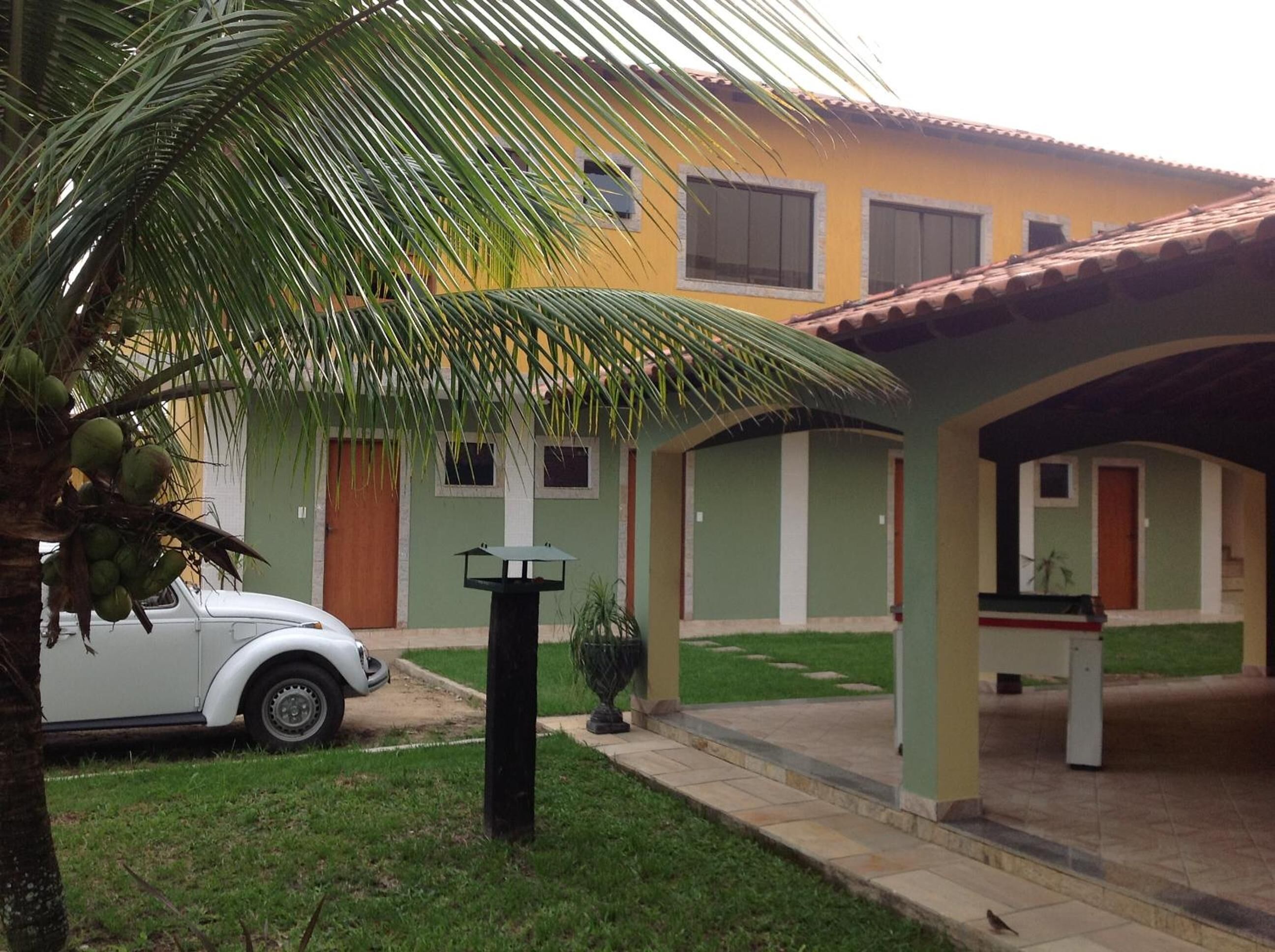 A two-story building with a covered patio area, a parked car, and a palm tree.