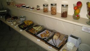 Noutopöytä, jossa on tarjolla monenlaista ruokaa, kuten hedelmiä, leivonnaisia ja erilaisia kastikkeita ja mausteita.