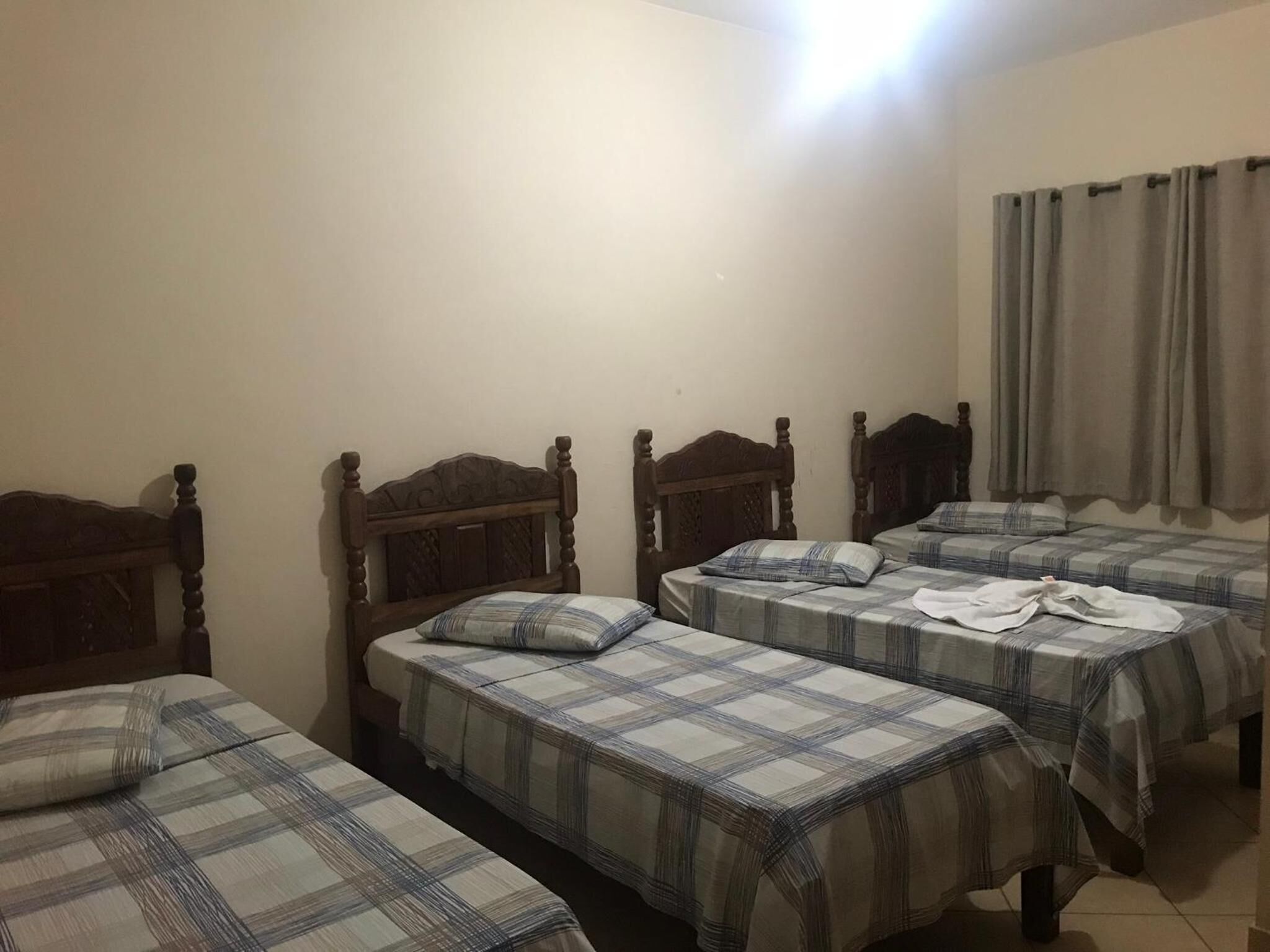 A room with four wooden beds, each with a plaid bedspread.