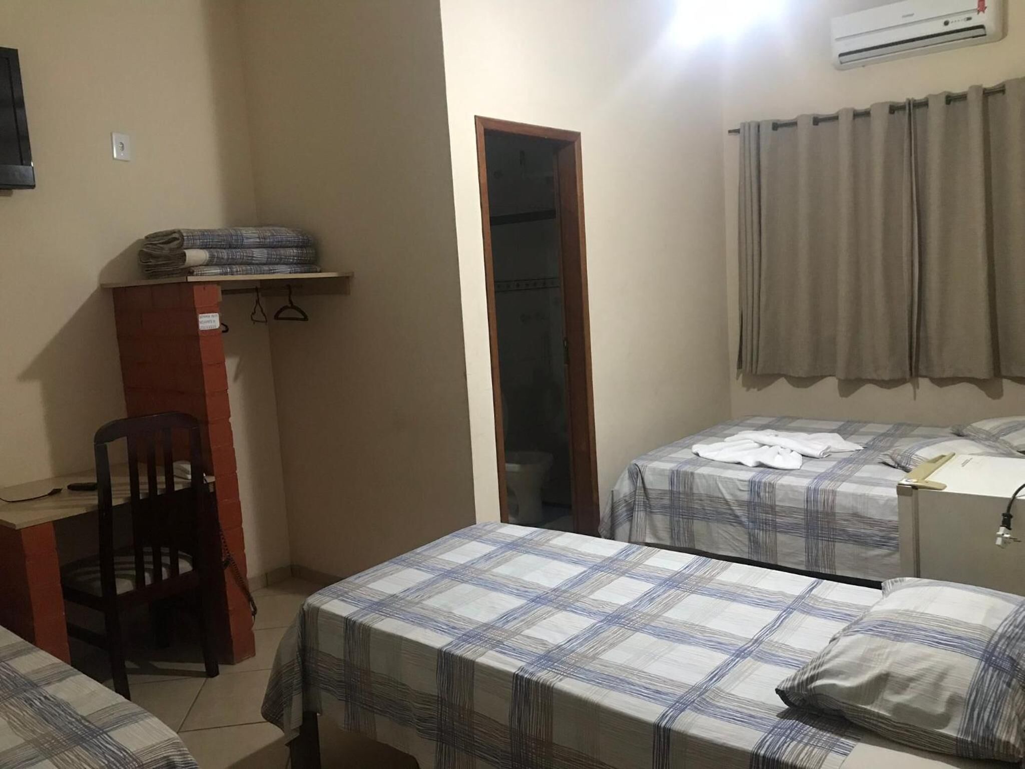 A small, compact room with two beds, a desk, and a chair.