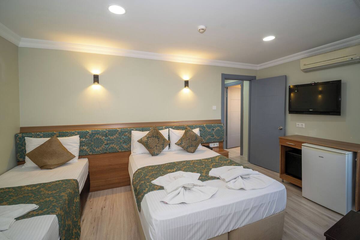 A hotel room with two beds, a TV, and a mini-fridge.