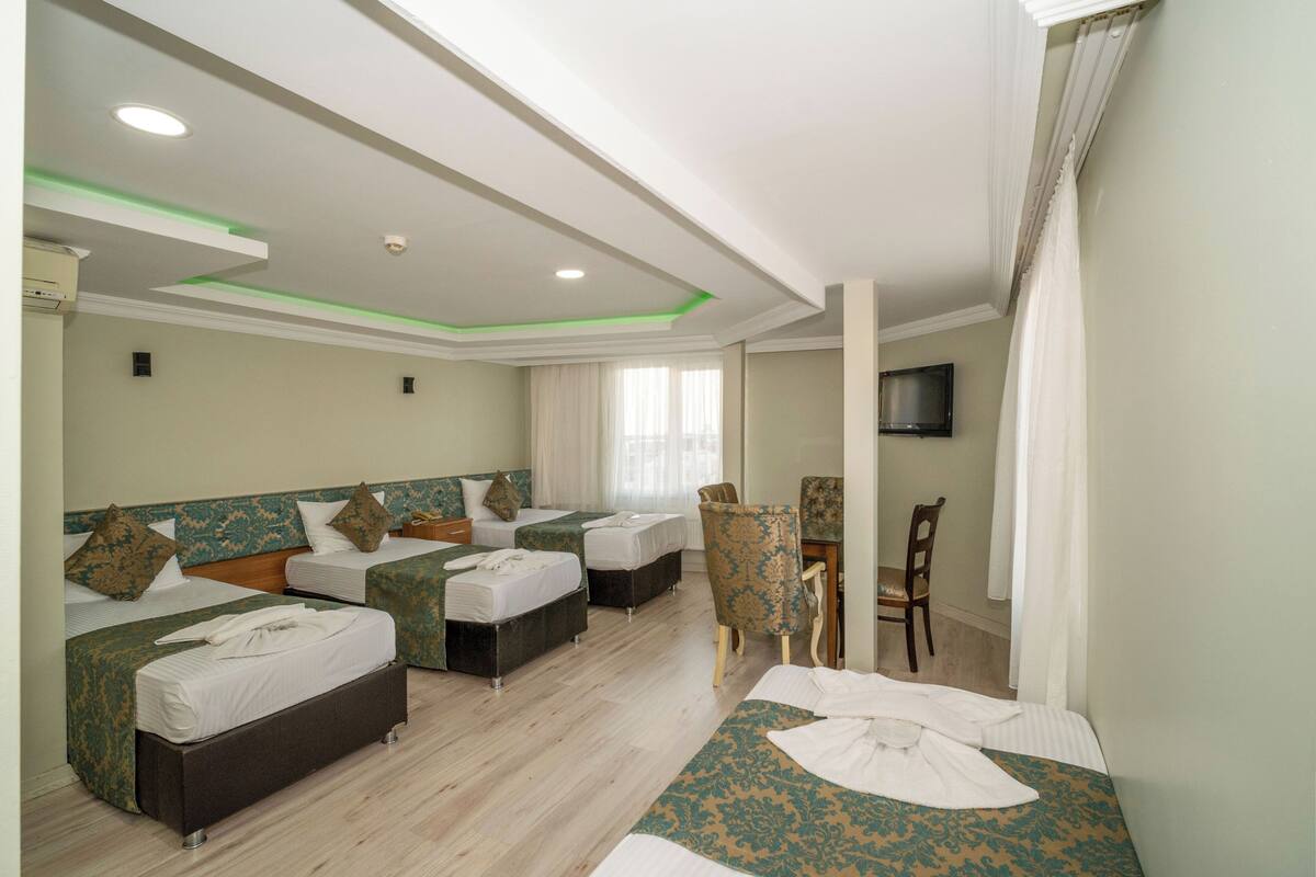 A hotel room with two beds, a desk, a chair, and a TV.