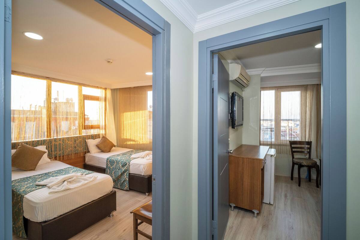 A hotel room with two beds, a desk, and a chair.