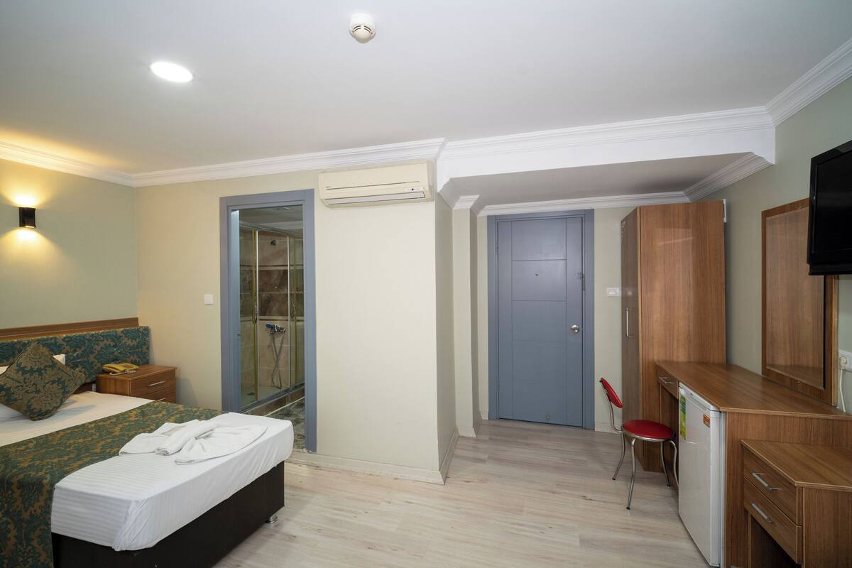 A hotel room with a bed, a desk, a chair, and a television.