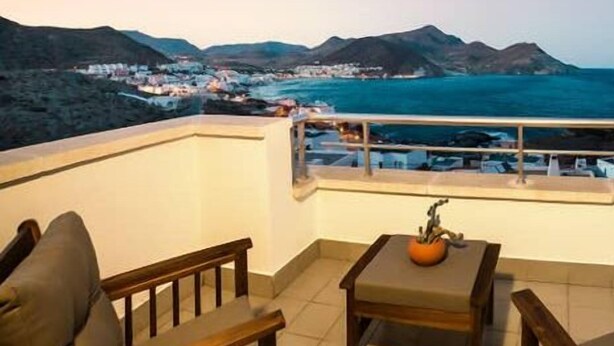 A balcony with a view of a coastal town and mountains. - Casa Hayman        . (Ventorros de San José)