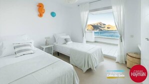 A hotel room with two beds, a view of the sea, and a beach visible through the window. - Casa Hayman        . (Ventorros de San José)