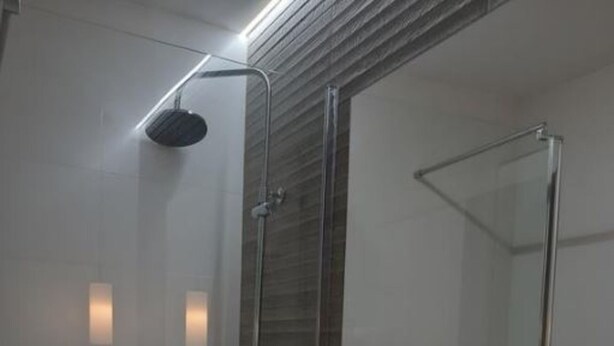 Une salle de bain moderne avec un grand miroir, un lavabo blanc et un espace douche.