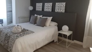 Un dormitorio con cama, mesitas de noche y decoración en la pared.